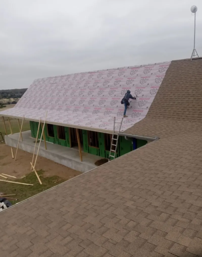 Worker preparing underlayment for a metal roof installation in Auburn